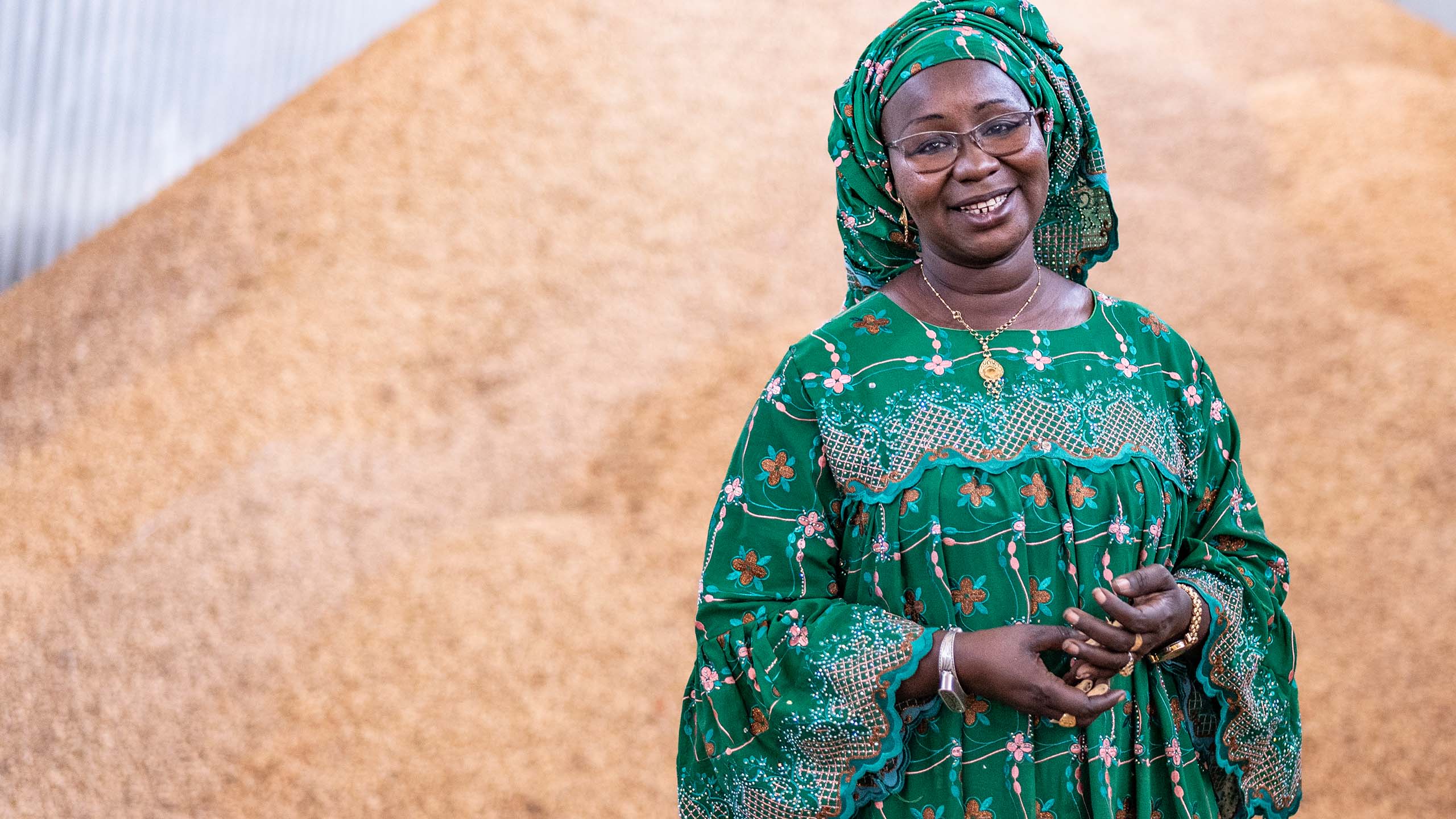 A portrait of a woman smiling in front of a large pile of peanuts.